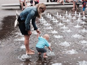 Woman with baby boy playing in a fountain